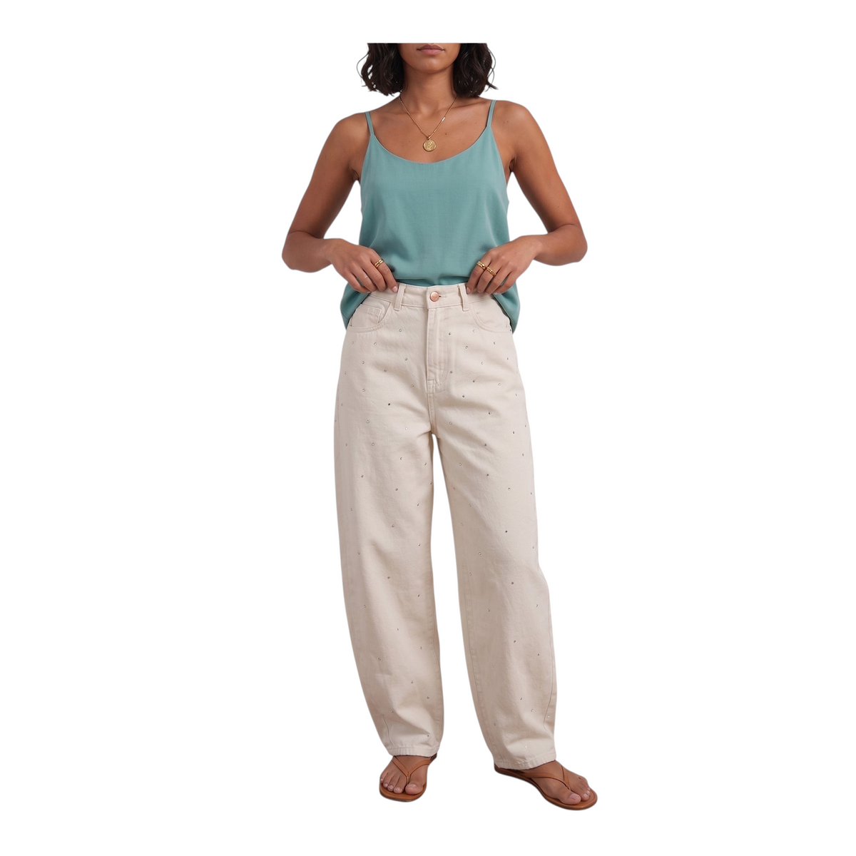 Modella indossa jeans palazzo color crema con applicazioni di Peg Fashion Store abbinati a un top verde acqua