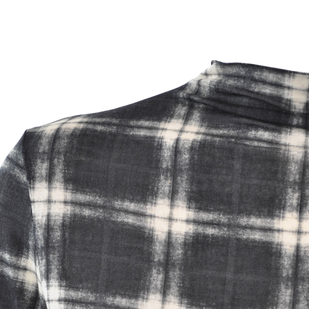 Dettaglio della spalla di una maglia in cachemire Peg Fashion Store con motivo a quadri bianco e nero